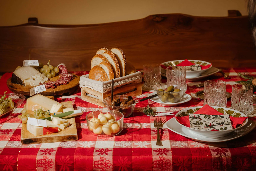Festively arranged holiday dining table with cheese, bread, fruits, and elegant glassware.