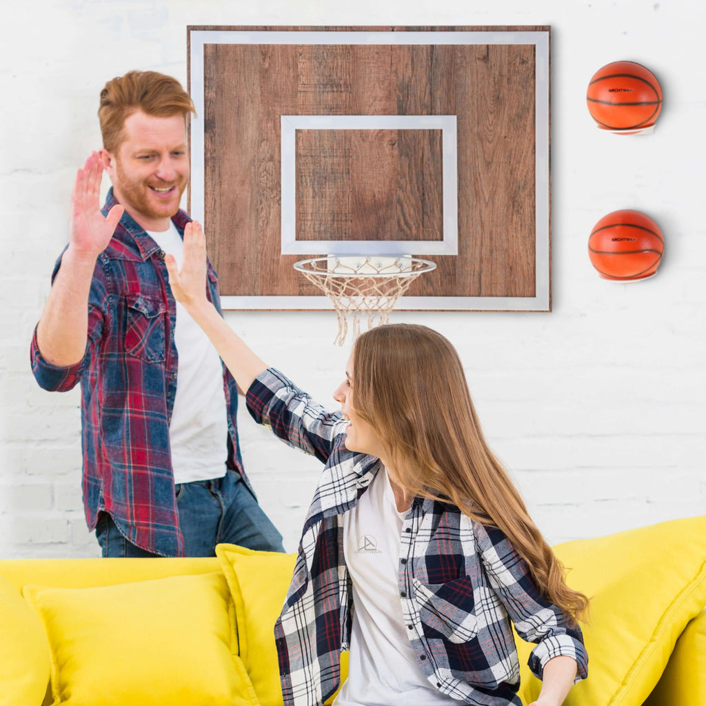 Two friends play basketball at home, sharing a fun moment in a cozy living room with a hoop and bright yellow couch.