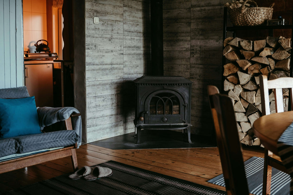 Cozy interior featuring a multi-purpose living space with a wood stove and stacked firewood.