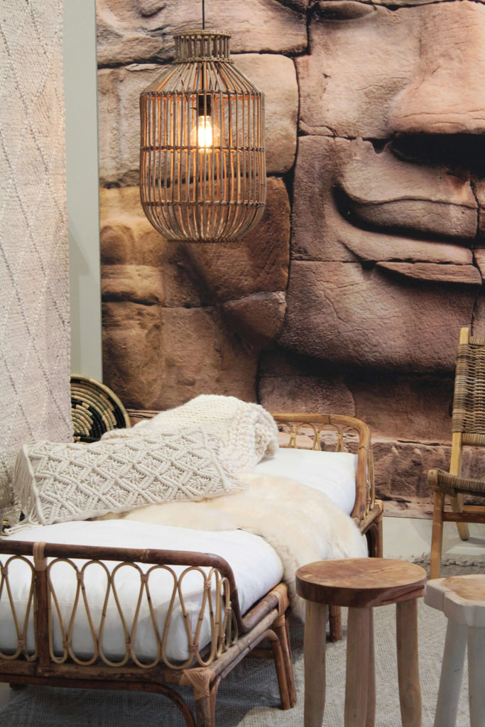 Cozy interior featuring a rattan daybed, warm lighting, and a serene stone mural background.