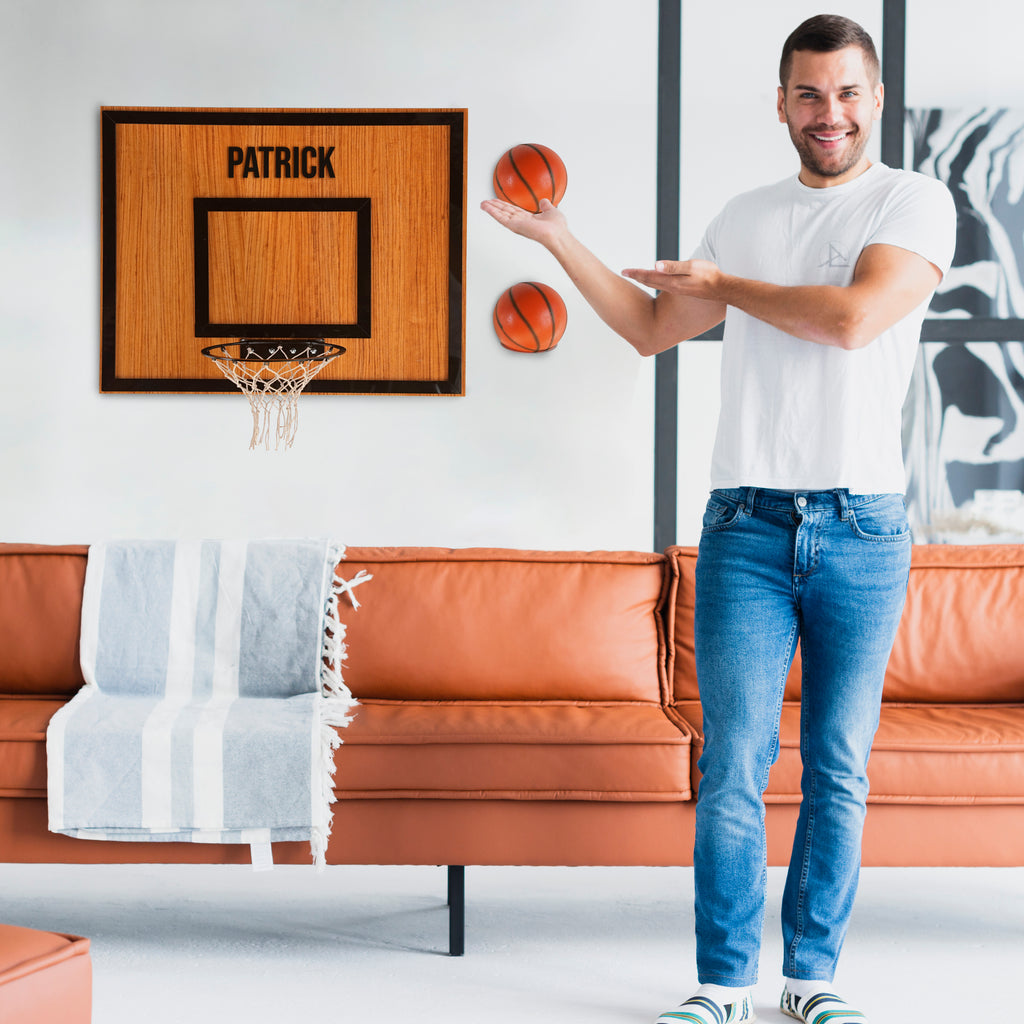Man holding basketball next to personalized wooden hoop named Patrick in a stylish living room.