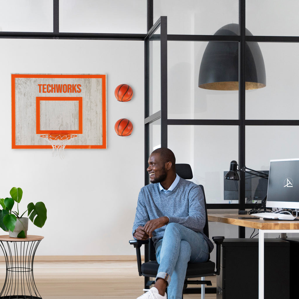 Man enjoying a stylish wooden wall hoop in a modern office setting, blending entertainment and sleek design.