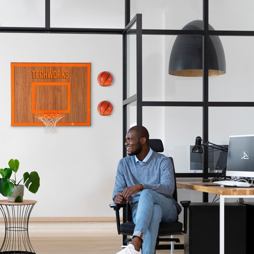 Man sitting in a modern office with a personalized wooden basketball hoop and decor.